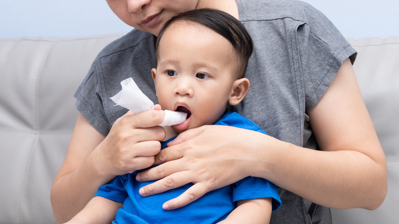 person wiping child's gums