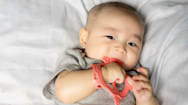 baby holding toy and looking curious