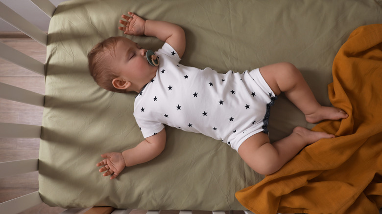 baby asleep in crib with pacifier in mouth