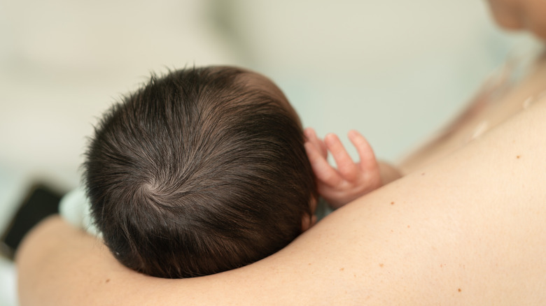 Newborn with a lot of dark hair being held