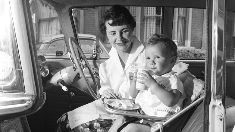 Mom smiling at toddler sitting in the front of the car in an early car seat