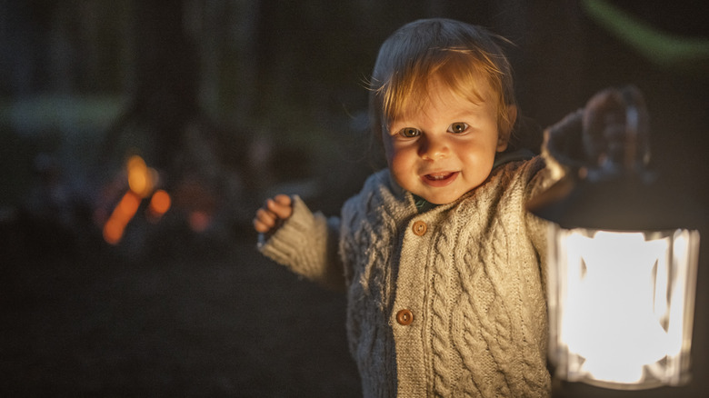 cozy baby with a lantern and fire in the background